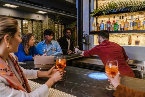 un groupe de personnes assises dans un bar avec des verres à vin dans l'établissement Mosaikon Glostel, à Athènes