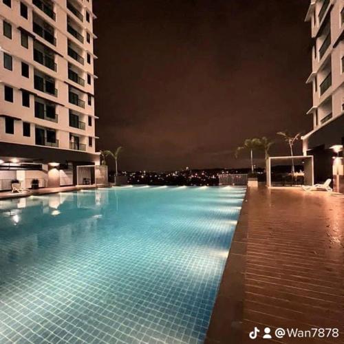 a large swimming pool at night with buildings at Nabiha Suites Bandar Baru Bangi in Bangi