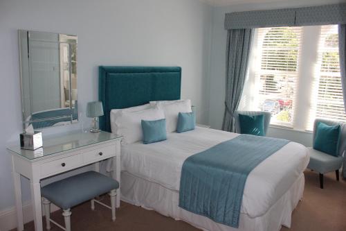 1 dormitorio con cama, escritorio y espejo en Trafalgar House, en Torquay