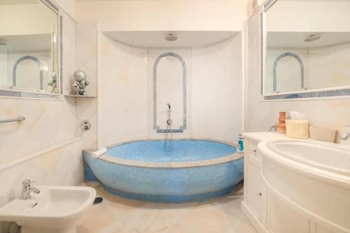 y baño con bañera azul y lavamanos. en Villa 4 Colonne, Capri en Capri