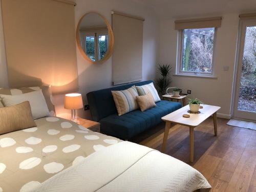 a living room with a blue couch and a mirror at Garden Studio in Benson