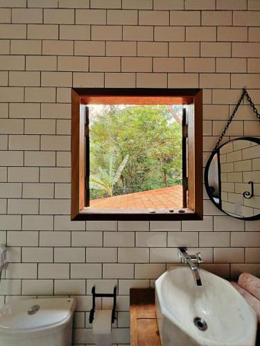 a bathroom with a sink and a mirror and a window at Casa Lipe & Rafa Linda casa com árvores in Lençóis