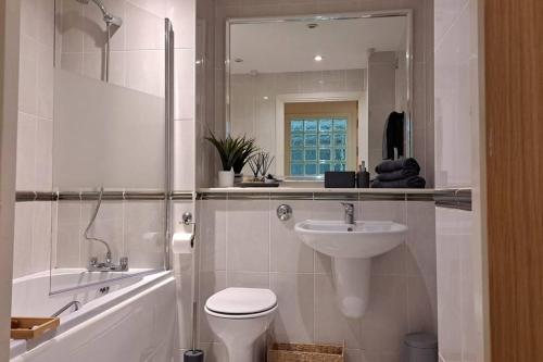 uma casa de banho com um lavatório, um WC e um espelho. em Spacious 2 Bed Perfect for City Centre & Bay, Pool, Gym em Cardiff