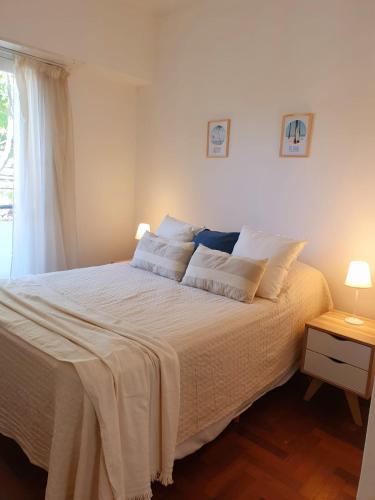 1 dormitorio con 1 cama grande con sábanas blancas y ventana en Depto MDQ en Mar del Plata