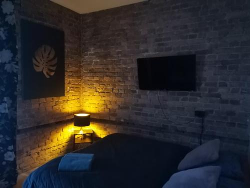 カトヴィツェにあるSilesia Noclegiのレンガの壁のベッドルーム(ベッド1台、ランプ付)