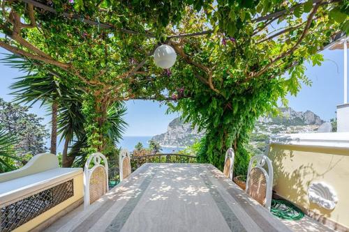 a wooden walkway with trees and a view of the ocean at Villa 4 Colonne, Capri in Capri