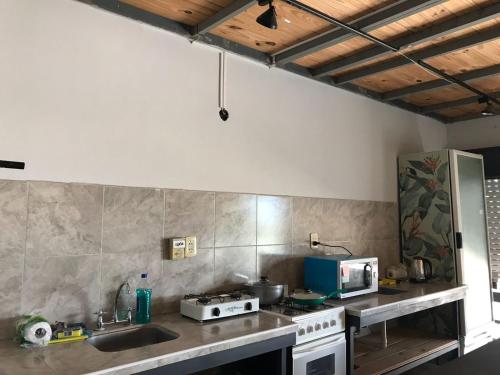 cocina con fregadero y fogones horno superior en Lapacho Hostel Salta Coliving en Salta