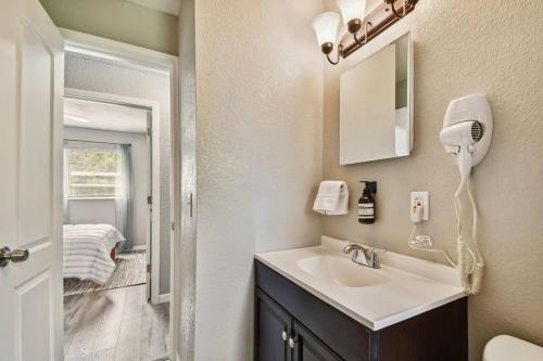 a bathroom with a sink with a hair dryer on the wall at ~ Modern and Cozy 4BR home - 30 Mins from Disney ~ in Orlando