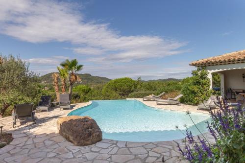 - une piscine avec des chaises et un rocher dans une cour dans l'établissement Le Mas de Heron, à Vidauban