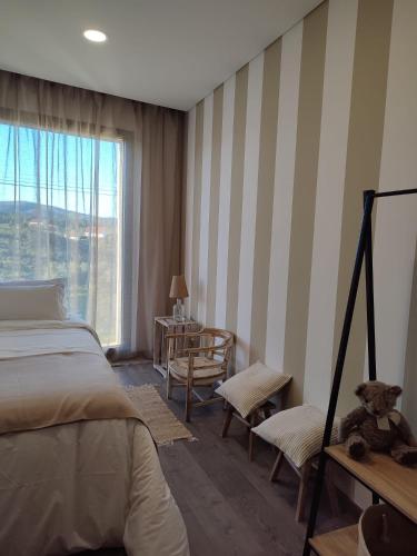 a bedroom with a bed and a window with a teddy bear at Raízes Turismo Rural in Castelo Branco