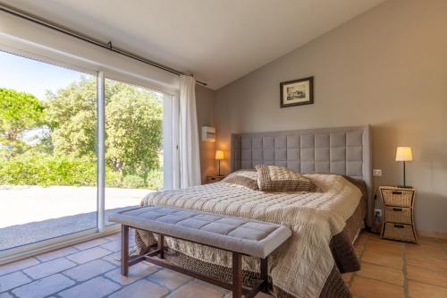 une chambre avec un lit et une grande fenêtre dans l'établissement Le Mas de Heron, à Vidauban