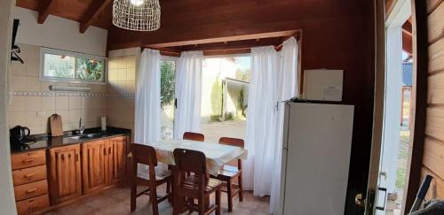 cocina con mesa y nevera en Cabaña Los Alamos en Dina Huapi