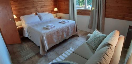 ein Hotelzimmer mit einem Bett und einem Sofa in der Unterkunft Cabaña Los Alamos in Dina Huapi