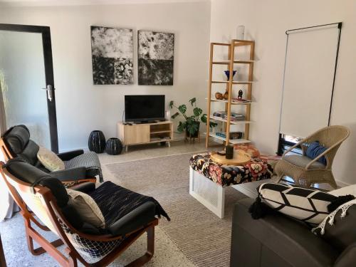 a living room with a couch and chairs and a tv at Sinclair Eco House in Port Lincoln