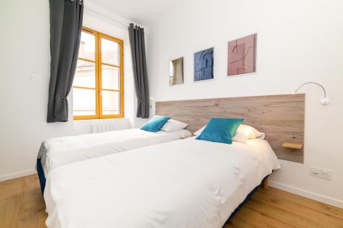 2 camas en una habitación con paredes blancas y ventana en La Dolive - Locationtournus en Tournus