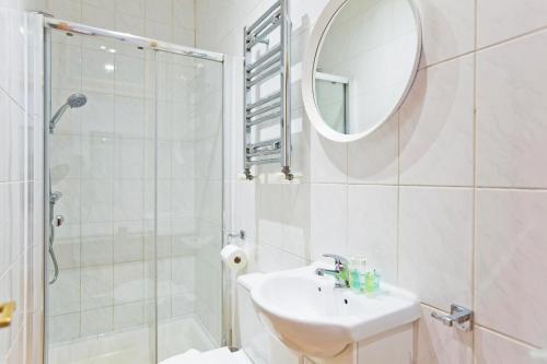 a bathroom with a sink and a shower and a mirror at Calabria 2 - Cosy apartment in London