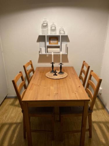 a wooden table with four chairs and two candles on it at Windalens på Österlen in Tomelilla