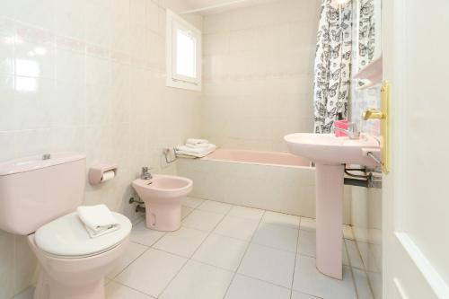 a white bathroom with a toilet and a sink at Apartaments Aiguablava in Begur