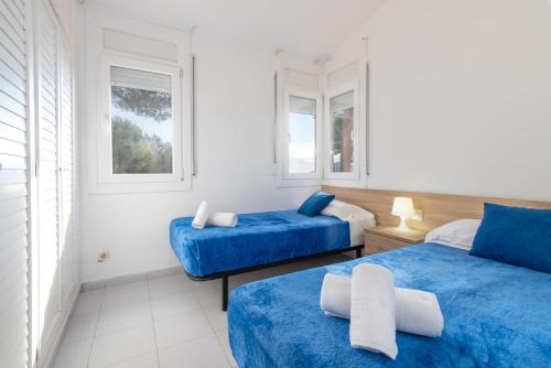 a bedroom with two blue beds and two windows at Apartaments Aiguablava in Begur