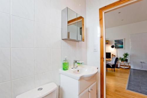 a white bathroom with a sink and a mirror at Calabria 4 Comfortable apartment in London