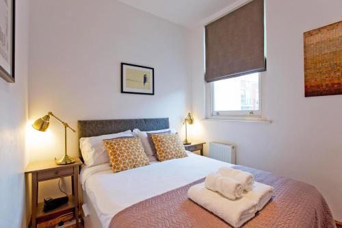ロンドンにあるComfortable Highbury Fields 1 Bedroom apartment - parking by requestのタオルが敷かれたベッドのある寝室