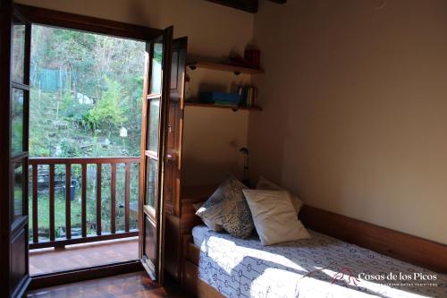een slaapkamer met een bed en een balkon met een raam bij Alojamiento turístico La Casuca de Kika - Casas de Los Picos in Pechón