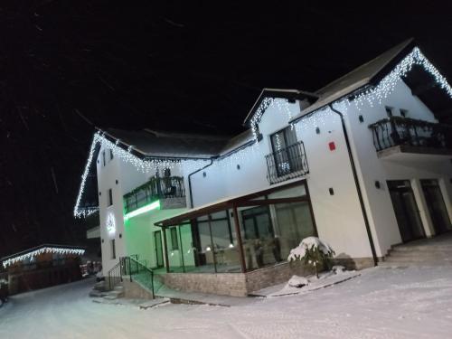 Un bâtiment avec des lumières de Noël dans la neige dans l'établissement Pensiunea Paradisul Verde, à Moisei