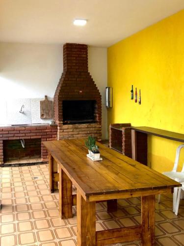 a living room with a wooden table and a fireplace at Casa Térrea Espaçosa Centro , Bertioga-Pertinho da Praia in Bertioga