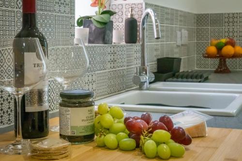 3 Anzac Cottage في كاوز: طاولة مطبخ مع زجاجة من النبيذ والعنب