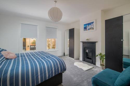 1 dormitorio con cama azul y chimenea en 3 Anzac Cottage, en Cowes