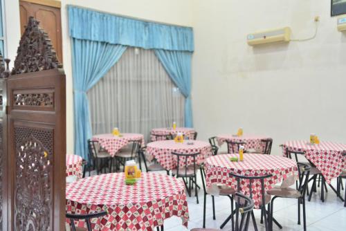 Hotel Mahkota في Pati: غرفة طعام مع طاولات وكراسي حمراء وبيضاء