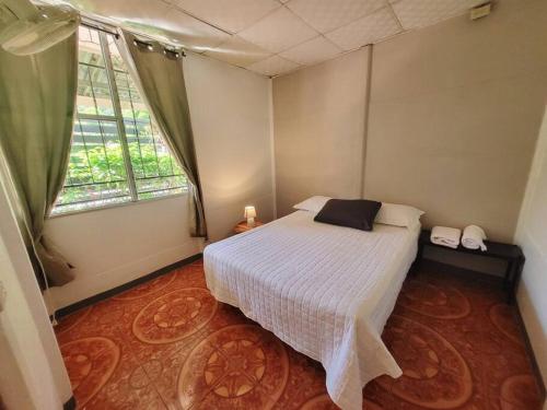 1 dormitorio con cama blanca y ventana en Casa Congo en Golfito