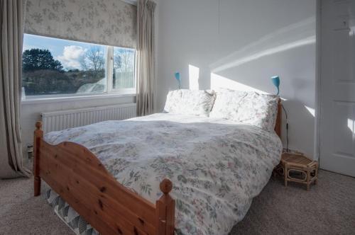 Schlafzimmer mit einem Bett und einem großen Fenster in der Unterkunft Maytree Cottage - 4 Bedroom Holiday Home - Tenby in Tenby
