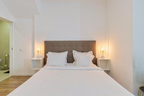 a bedroom with a large white bed with two lamps at Garrett House in Setúbal