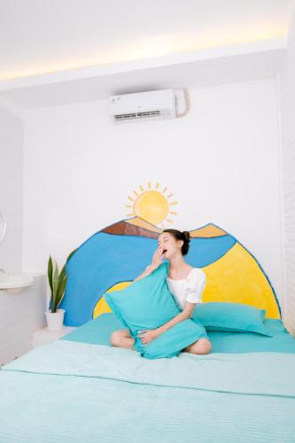 a woman sitting on top of a bed at Roemah Renjana Yogyakarta in Timuran