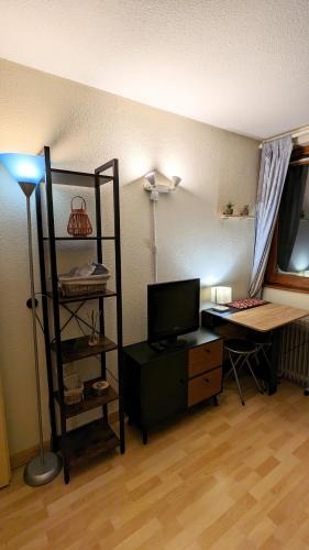 un salon avec un bureau, une télévision et une lampe dans l'établissement Appartement La Mongie au pied des pistes, à Bagnères-de-Bigorre