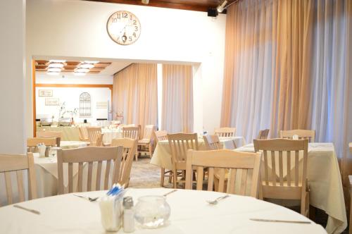 a restaurant with tables and chairs and a clock on the wall at Rila Hotel Sofia in Sofia