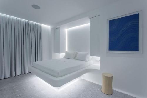 um quarto branco com uma cama e um quadro azul em Super Luxury Mykonos Villa - Villa Saorsa - 5 Bedroom - Infinity Pool - Panoramic Sea Sunset Views em Dexamenes