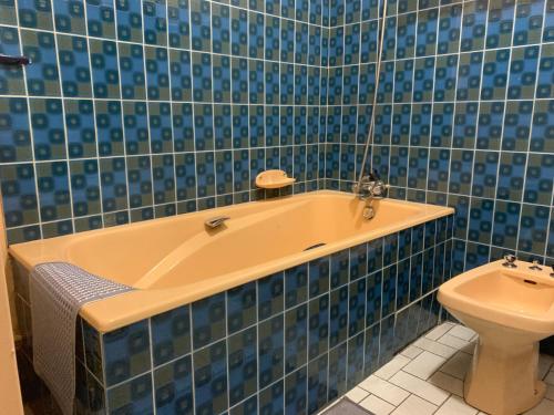 La salle de bains est pourvue de carrelage bleu, d'une baignoire et de toilettes. dans l'établissement Appartement proche basilique Saint Rémi, à Reims