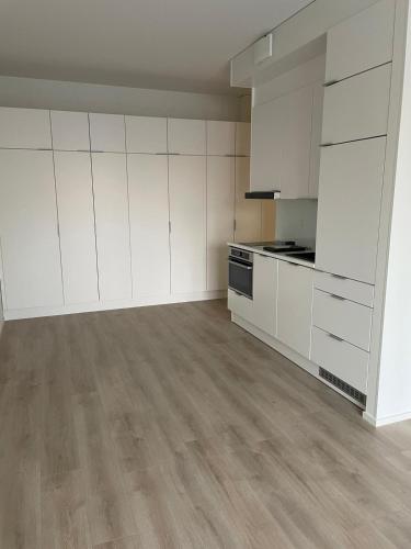 an empty kitchen with white cabinets and wooden floors at Snow Queen's residence in Rovaniemi