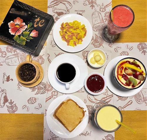 una mesa con platos de comida y bebida y un libro en Hotel Cisne en Cuenca