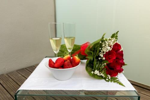 a table with a bowl of strawberries and two glasses of wine at Hotel Laranjeira in Viana do Castelo