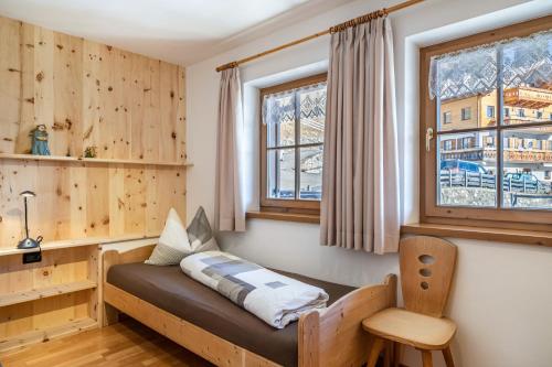 Bett in einem Zimmer mit Holzwänden und Fenstern in der Unterkunft Kalchgruberhof Wohnung Alpenrose in Ulten