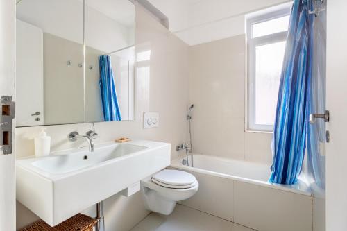 a white bathroom with a sink and a toilet and a window at JOIVY Chic 2BR Apt in Bairro Alto, 2mins to São Pedro de Alcântara viewpoint in Lisbon