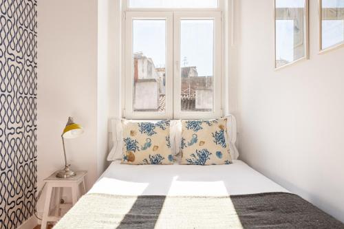 a small bedroom with a bed and a window at JOIVY Chic 2BR Apt in Bairro Alto, 2mins to São Pedro de Alcântara viewpoint in Lisbon