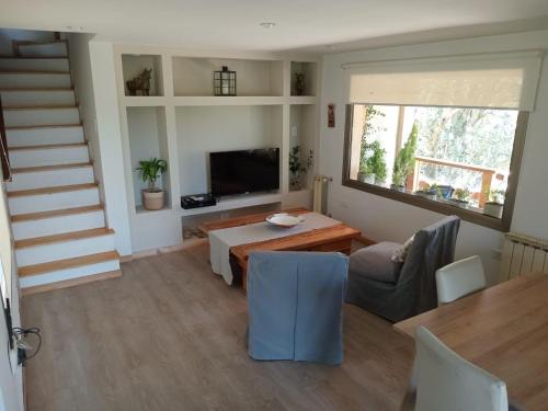 a living room with a table and chairs and a television at Casa de Huéspedes Villa Pehuenia in Villa Pehuenia