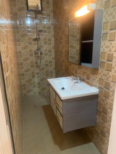 a bathroom with a sink and a shower with a mirror at Auberge Keur Ely in Ouoran