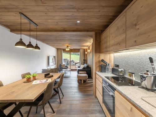 une cuisine et une salle à manger avec une longue table en bois dans l'établissement Charmant appartement à Courchevel Le Praz, proche des pistes, 4 adultes | 1 enfant, services inclus - FR-1-568-22, à Courchevel