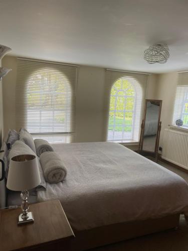 a bedroom with a large bed and two windows at Ground floor apartment in The Coach House in Hartford