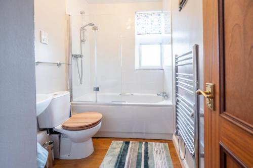 a bathroom with a toilet and a tub and a sink at Flat 3, Abbey House in Binham